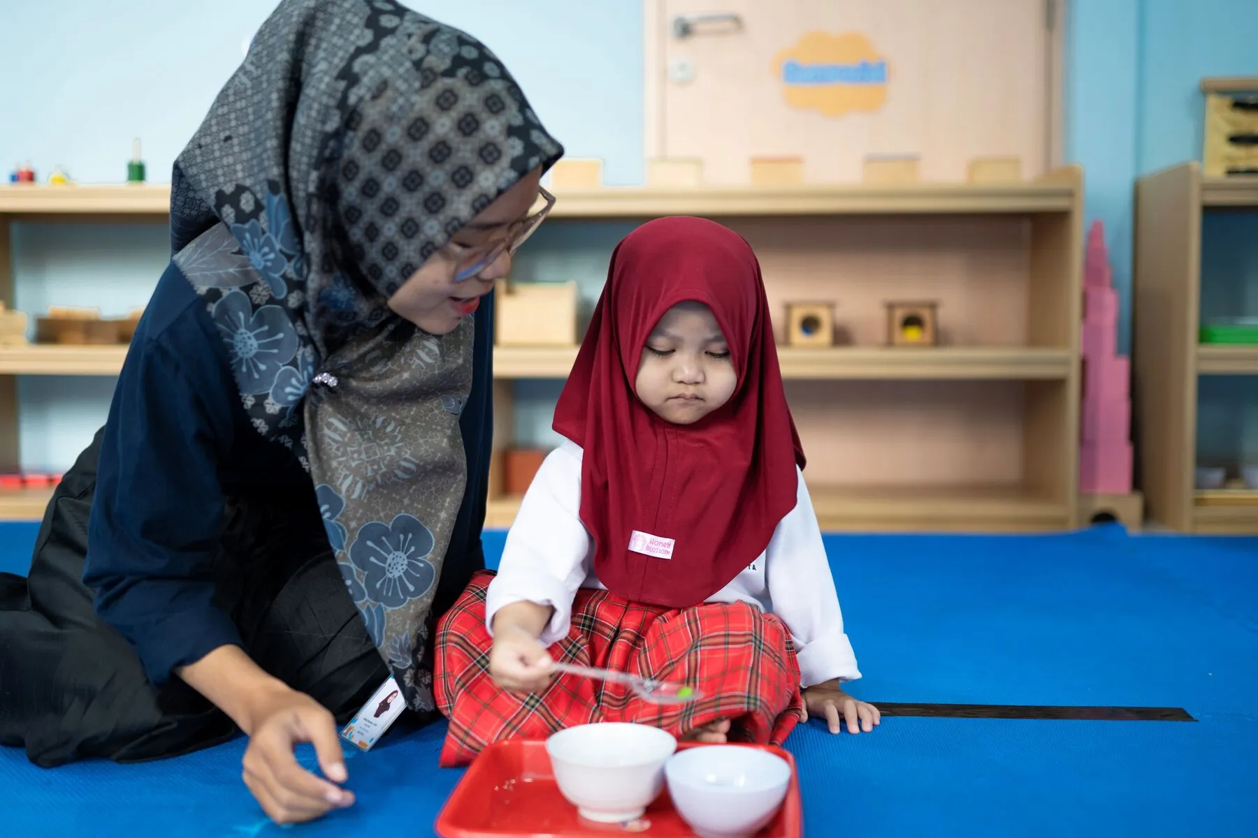 Siswi menuang biji-bijian dalam kegiatan Montessori