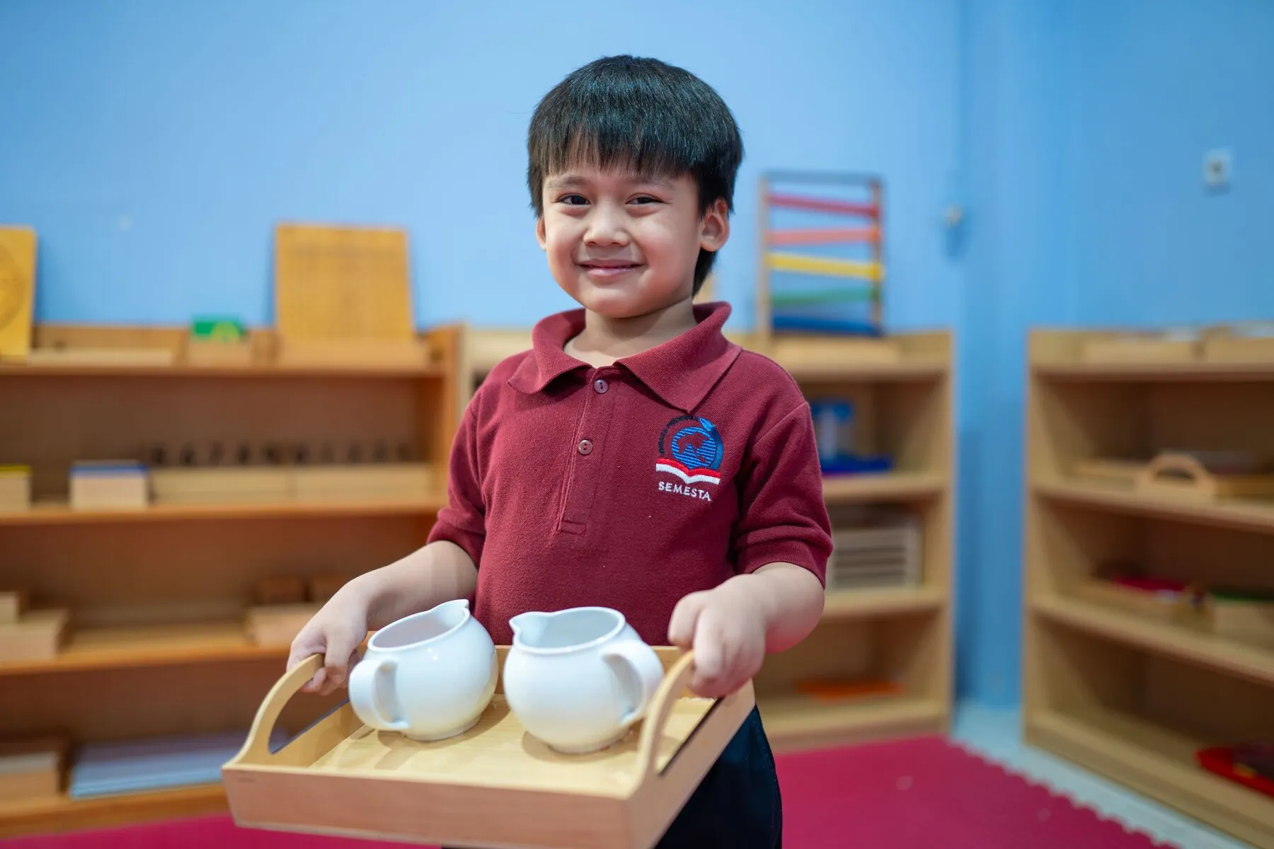 Siswa membawa nampan teko dalam kegiatan practical life Montessori