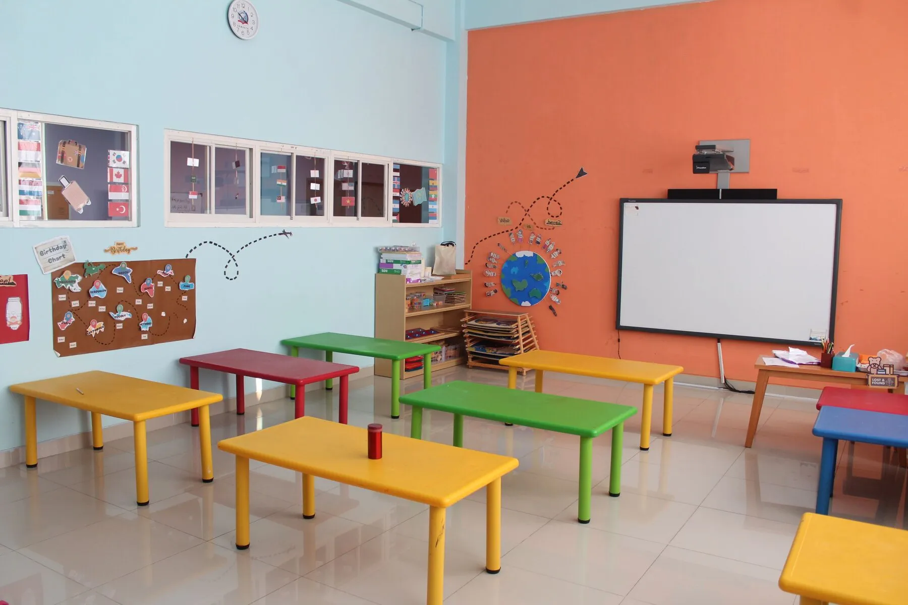 Ruang Montessori dengan rak-rak material dan karpet merah
